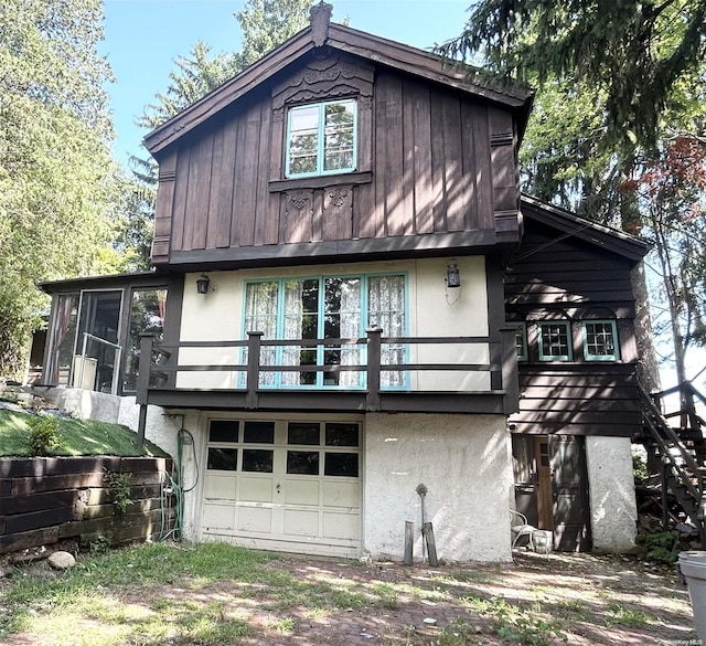 back of property with a sunroom, a balcony, and a garage