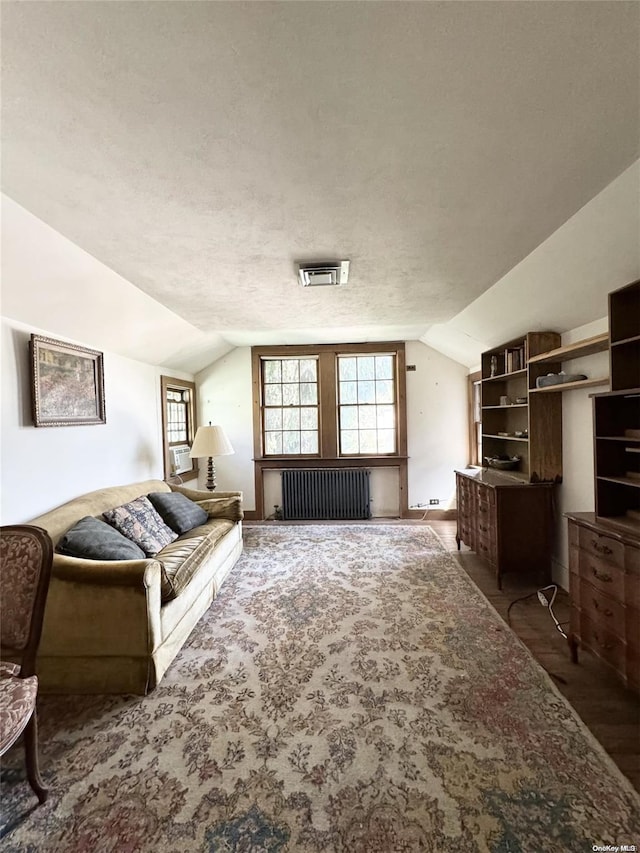 living room featuring a textured ceiling, dark hardwood / wood-style floors, radiator, and lofted ceiling