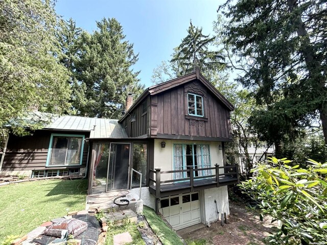 329 Forest Rd, Little Neck, NY 11363 - back of property with a chimney, an attached garage, a yard, a standing seam roof, and metal roof