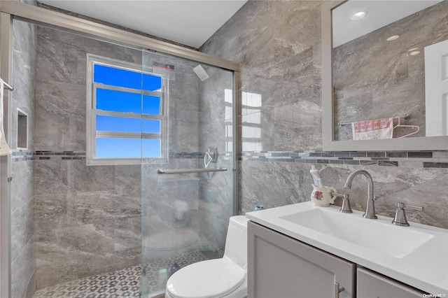 bathroom featuring walk in shower, vanity, toilet, and tile walls