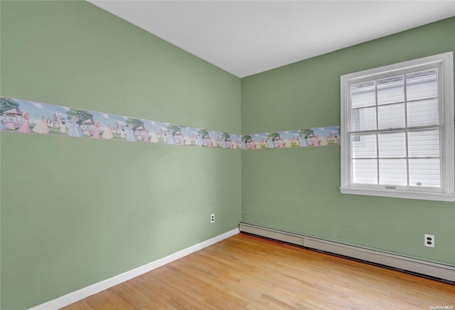 unfurnished room featuring light hardwood / wood-style floors and a baseboard heating unit