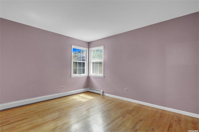 unfurnished room with wood-type flooring and a baseboard radiator