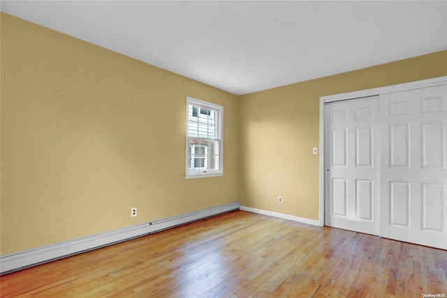 unfurnished bedroom with a closet, light wood-type flooring, and a baseboard radiator