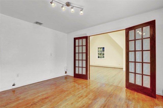 unfurnished room with french doors, light hardwood / wood-style flooring, and lofted ceiling