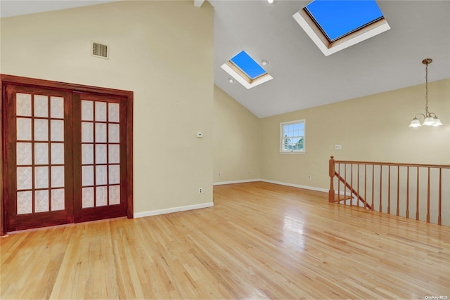 unfurnished room with high vaulted ceiling, light hardwood / wood-style floors, and an inviting chandelier