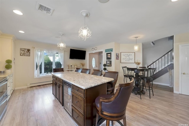 kitchen with dark brown cabinetry, a baseboard radiator, a notable chandelier, pendant lighting, and light hardwood / wood-style floors