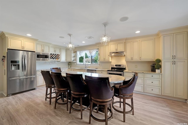 kitchen with appliances with stainless steel finishes, light hardwood / wood-style flooring, pendant lighting, and cream cabinets