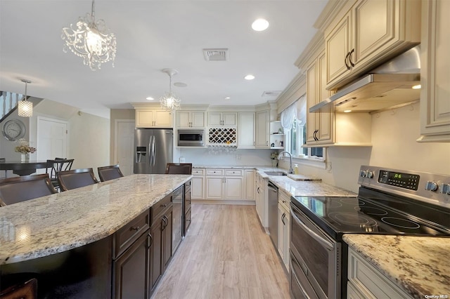 kitchen with appliances with stainless steel finishes, a kitchen breakfast bar, sink, a notable chandelier, and light hardwood / wood-style floors