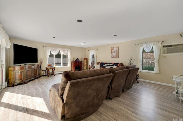 living room with a wall mounted air conditioner and light wood-type flooring