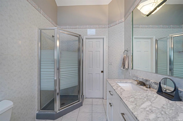 bathroom with an enclosed shower, vanity, toilet, and tile walls