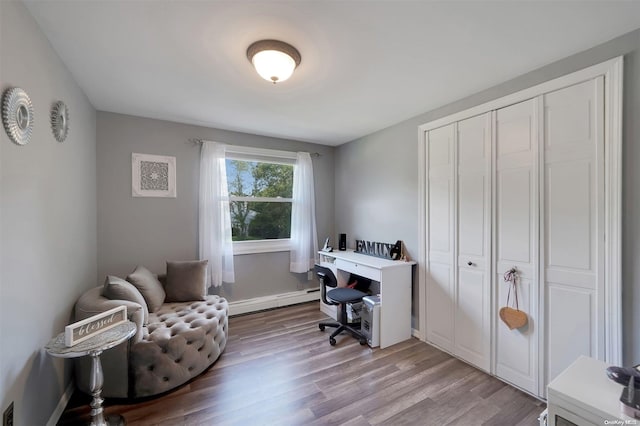 home office with light hardwood / wood-style flooring and a baseboard heating unit