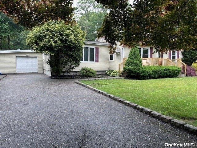 view of property hidden behind natural elements featuring a front lawn and a garage