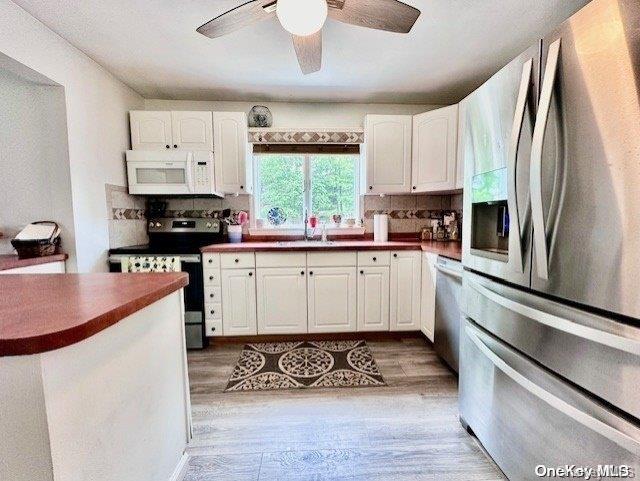 kitchen featuring tasteful backsplash, white cabinetry, appliances with stainless steel finishes, and light hardwood / wood-style flooring