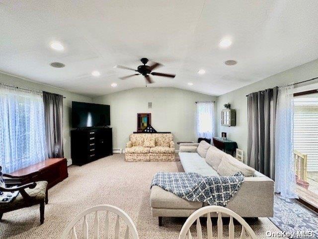 living room with ceiling fan, light colored carpet, and lofted ceiling