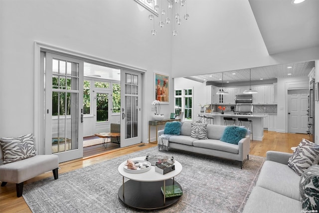 living room with french doors, a high ceiling, and light wood-type flooring