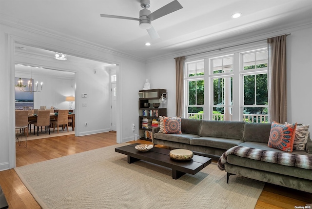 living room featuring ceiling fan with notable chandelier, light hardwood / wood-style floors, and ornamental molding