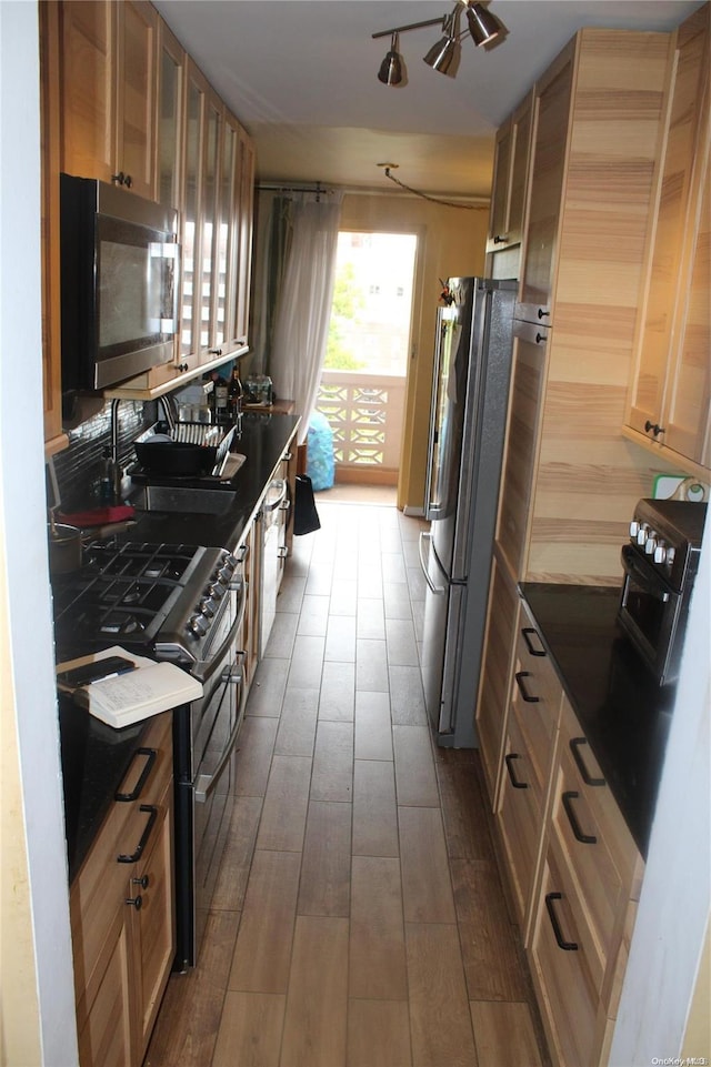 kitchen featuring hardwood / wood-style flooring, ceiling fan, appliances with stainless steel finishes, and track lighting