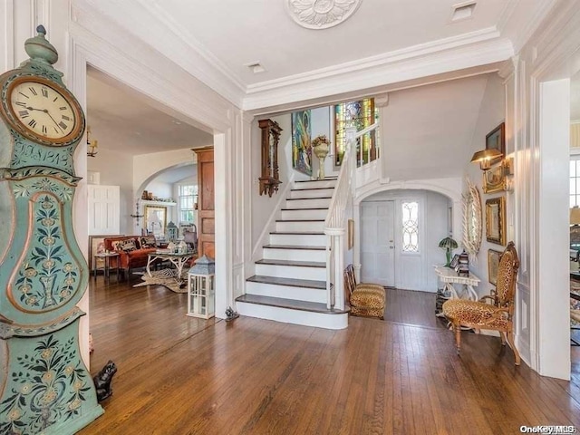 entryway with dark hardwood / wood-style flooring, ornamental molding, and vaulted ceiling