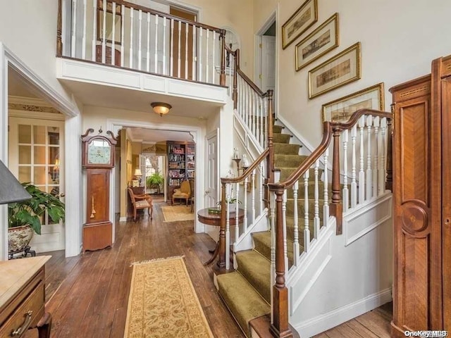 entrance foyer with dark hardwood / wood-style flooring and a towering ceiling