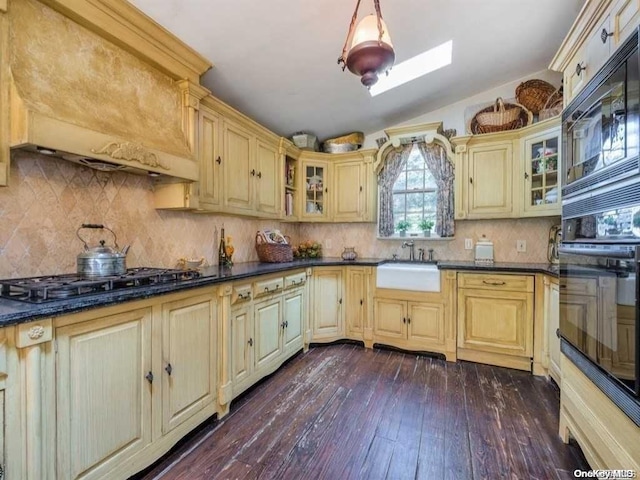 kitchen featuring decorative backsplash, premium range hood, sink, and dark wood-type flooring