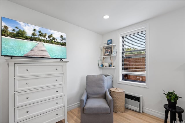 sitting room with heating unit and light hardwood / wood-style flooring