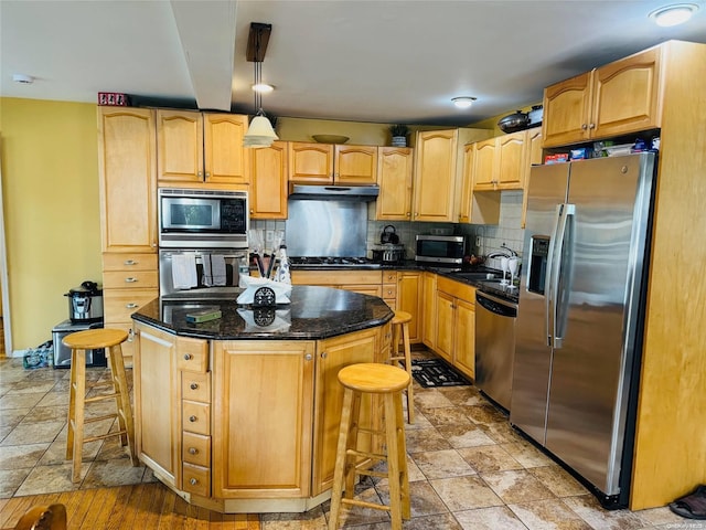 kitchen featuring appliances with stainless steel finishes, backsplash, a breakfast bar, a kitchen island, and hanging light fixtures