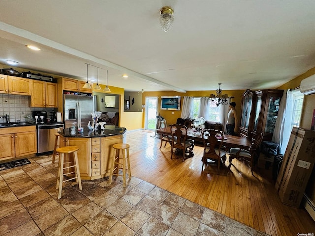 kitchen with appliances with stainless steel finishes, hardwood / wood-style flooring, a kitchen island, hanging light fixtures, and a breakfast bar area