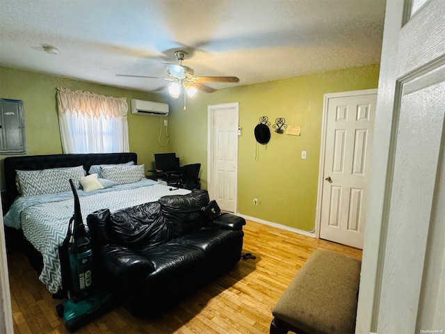 bedroom with a wall mounted air conditioner, ceiling fan, and wood-type flooring