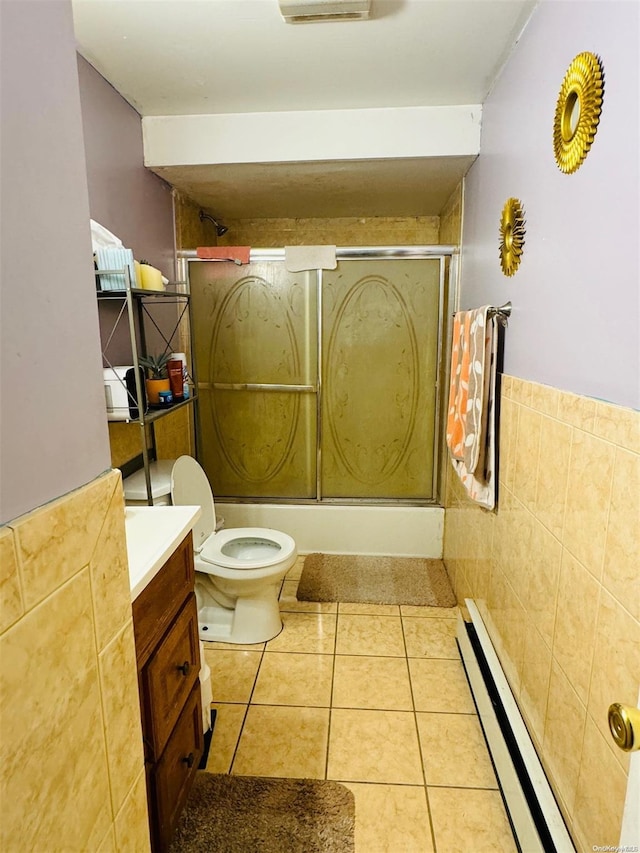 full bathroom featuring tile patterned flooring, toilet, shower / bath combination with glass door, vanity, and tile walls