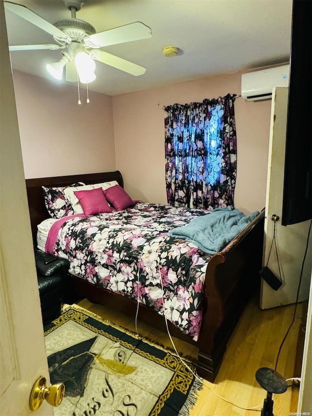 bedroom featuring light hardwood / wood-style flooring, an AC wall unit, and ceiling fan