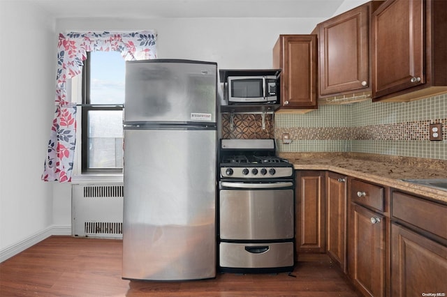 kitchen with tasteful backsplash, radiator, dark hardwood / wood-style flooring, and appliances with stainless steel finishes