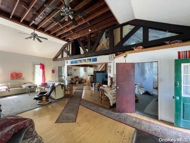 living room with beam ceiling, high vaulted ceiling, and wood-type flooring