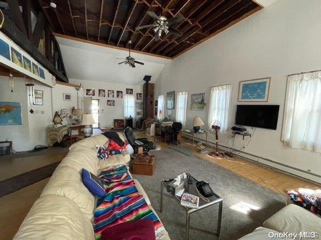 tiled living room with plenty of natural light, ceiling fan, and lofted ceiling