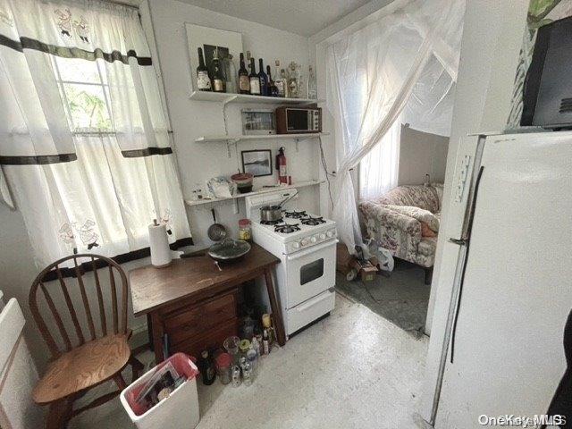 kitchen featuring a wealth of natural light, white cabinets, and white gas range oven