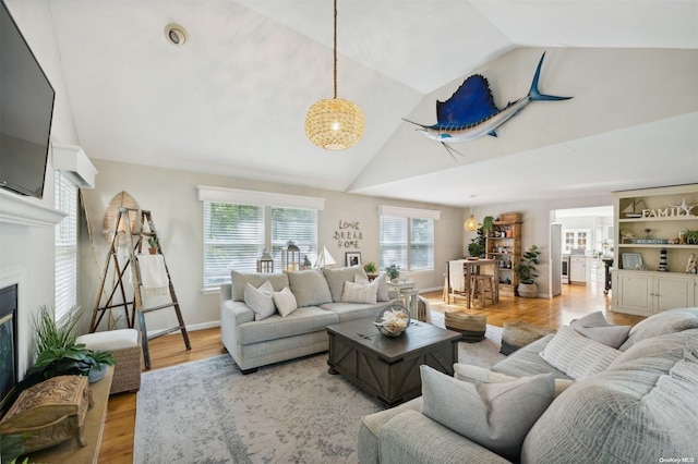 living room featuring vaulted ceiling, a wealth of natural light, and light hardwood / wood-style flooring