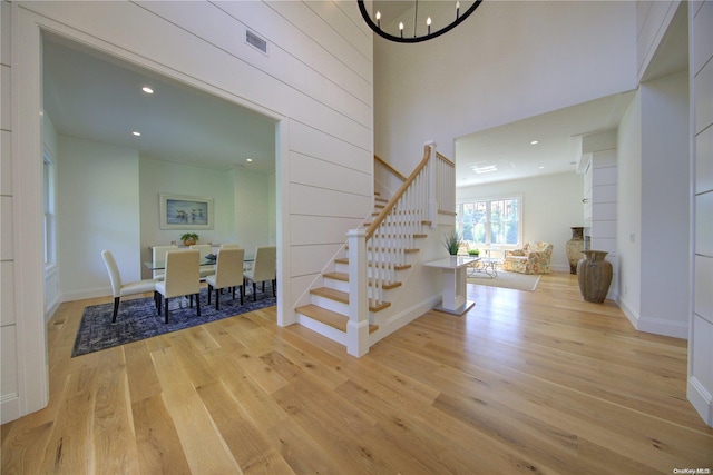 stairway featuring a chandelier, a high ceiling, and hardwood / wood-style flooring