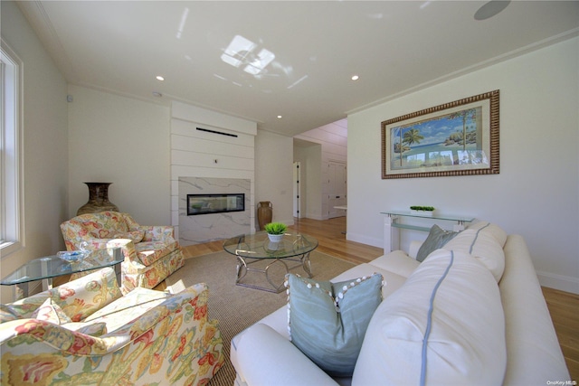 living room with a high end fireplace, light wood-type flooring, and ornamental molding