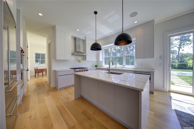 kitchen featuring pendant lighting, wall chimney exhaust hood, a healthy amount of sunlight, and light wood-type flooring