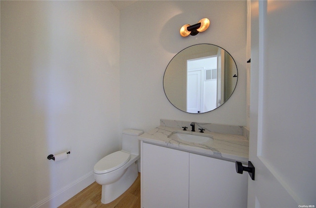 bathroom featuring wood-type flooring, vanity, and toilet