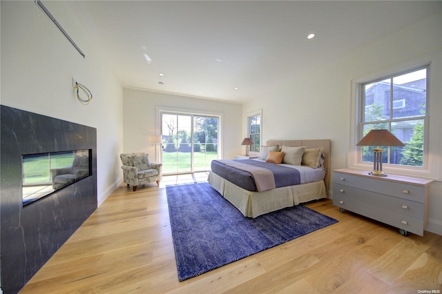 151 Newtown Ln, East Hampton, NY 11937 - bedroom with access to exterior, light wood finished floors, a glass covered fireplace, recessed lighting, and baseboards