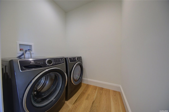 clothes washing area featuring washer and dryer and light hardwood / wood-style flooring