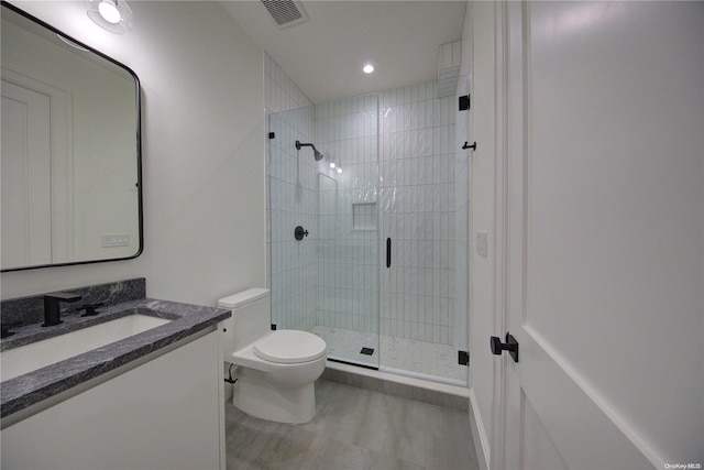 bathroom with vanity, toilet, and a shower with shower door