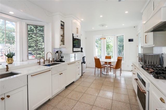 kitchen featuring premium range hood, stainless steel appliances, a healthy amount of sunlight, sink, and white cabinets