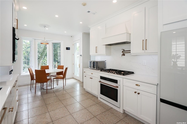 kitchen featuring tasteful backsplash, custom exhaust hood, white appliances, decorative light fixtures, and white cabinets