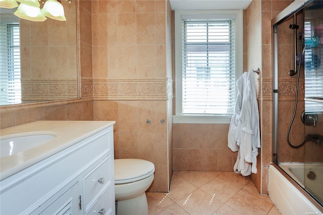 full bathroom with tile patterned flooring, combined bath / shower with glass door, toilet, vanity, and tile walls