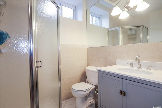 bathroom featuring tile patterned floors, vanity, tile walls, toilet, and a shower with shower door