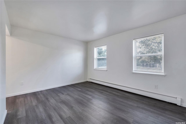 unfurnished room with baseboard heating and dark wood-type flooring