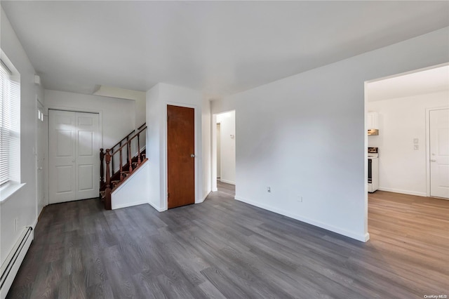 unfurnished living room featuring dark hardwood / wood-style floors and a baseboard heating unit