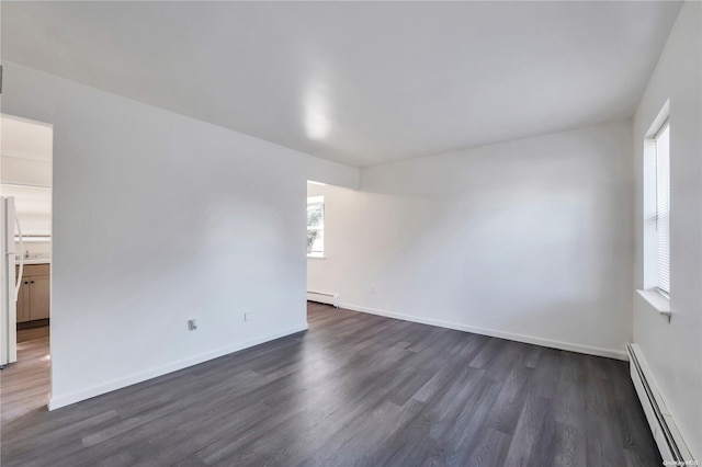 spare room featuring dark wood-type flooring and a baseboard heating unit