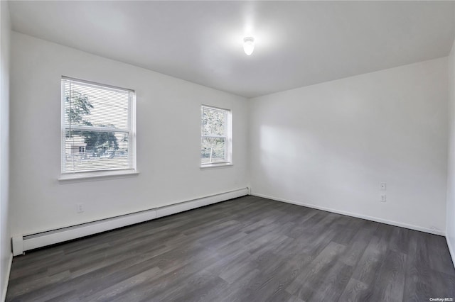 spare room with dark hardwood / wood-style floors and a baseboard heating unit